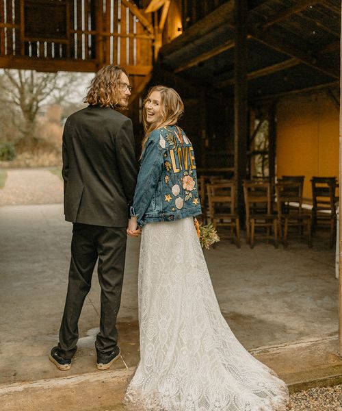 Groom in black tie with bride in lace Rosa Clara dress and bespoke embroidered denim jacket. 