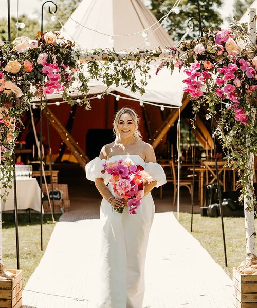 Tipi wedding with the bride in off the shoulder dress holding pink bouquet