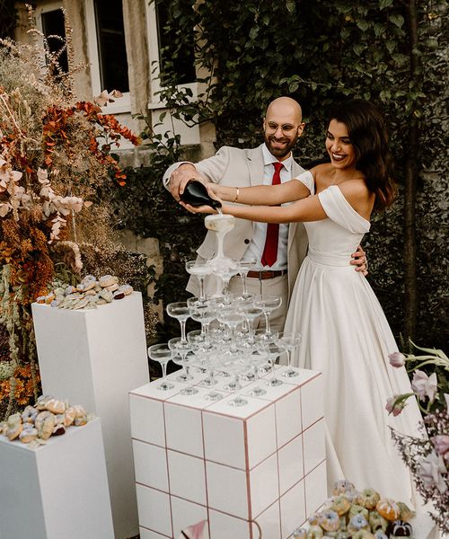 Bride and groom pour their champagne tower for their wedding at Chapel House Estate.