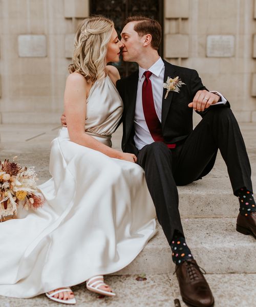 Bride in a champagne colour wedding dress kissing her groom on the steps at Leeds Civic Hall 