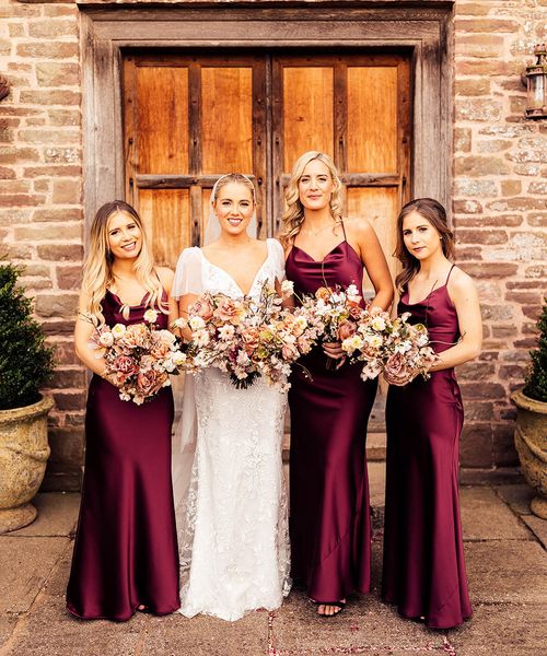 Bride in Emmy Mae bridal gown and bridesmaids in burgundy satin bridesmaid dresses.