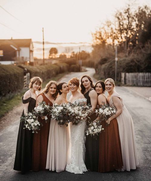 Bride in lace Maggie Sottero wedding dress with bridesmaids in earth toned dresses for wedding at Cooling Castle Barn.