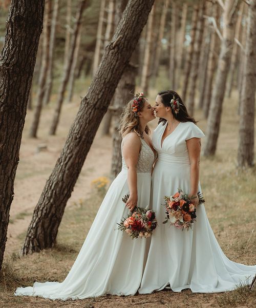 Bride in Freda Bennett wedding dress kissing the other bride for their outdoor wedding.