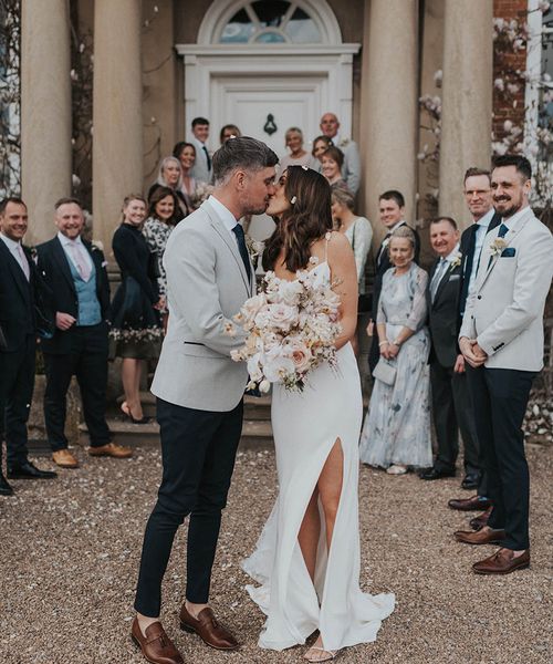 Bride in Alexandra Grecco wedding dress with split leg with groom. 