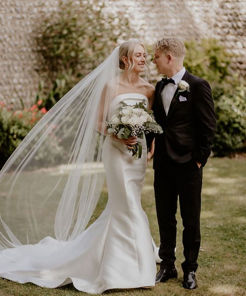 Bride and groom pose together for their Cissbury Barns black tie wedding.