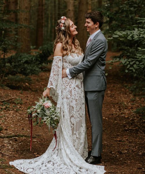 Bride in strapless lace medieval wedding dress with custom sleeves with groom in woodland after handfasting ceremony. 