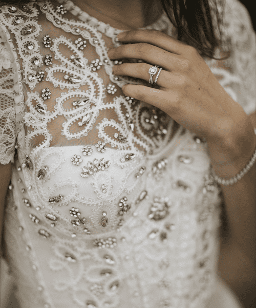 Bride in a bejewelled wedding dress wearing a sparkly engagement and wedding ring.