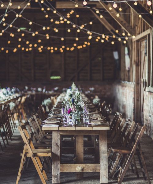 Rustic wedding ideas with fairy lights, trestle tables, tree slices, flowers in jars and wooden signs 