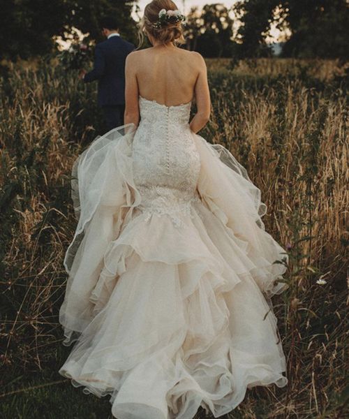 Mermaid wedding dress worn by the bride running through a field.