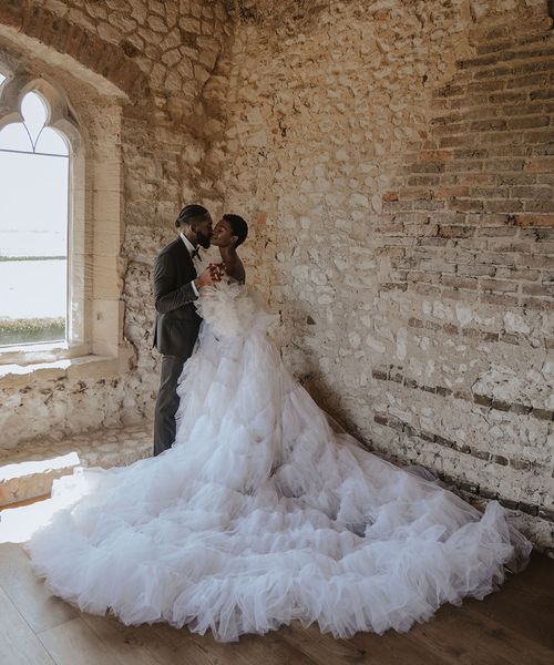 Bride wearing a statement tulle Millia London wedding dress with groom in black tuxedo