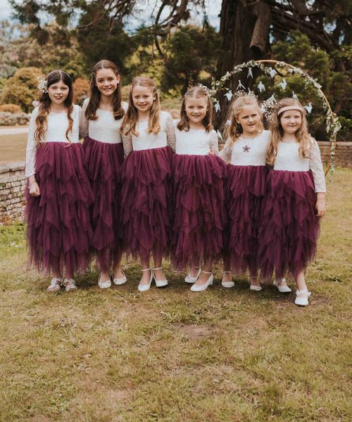 Six flower girls in purple tulle layered flower girl dresses with lace top detail