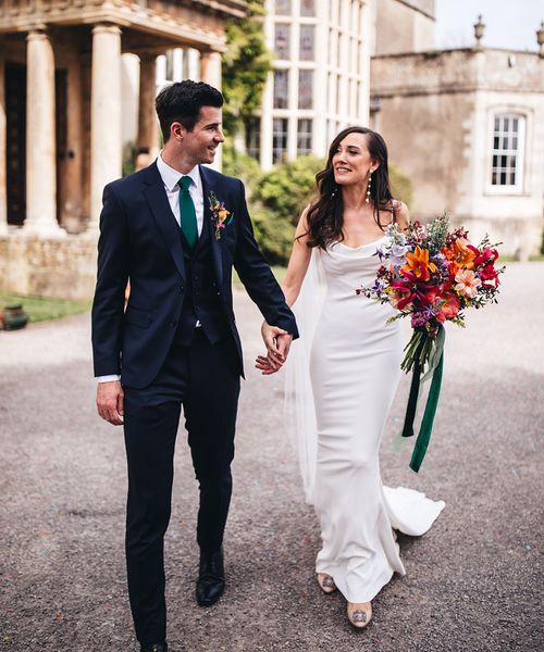 Kyha wedding dress worn by bride walking with groom at Elmore Court.