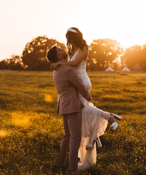 bride is lifted up by the groom for their golden hour wedding photos