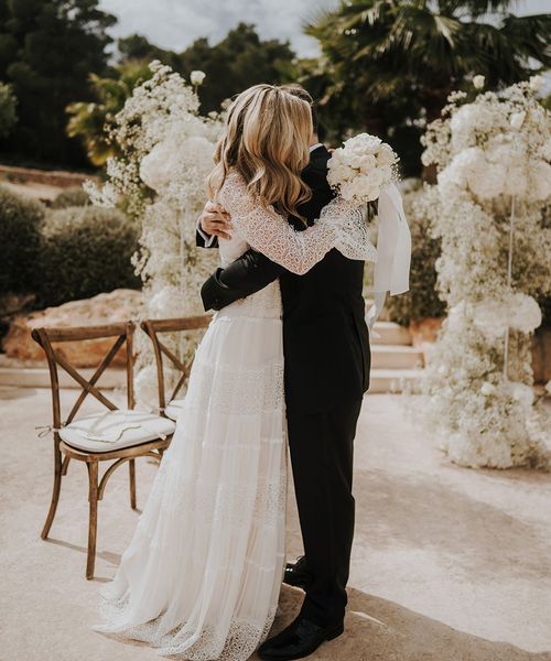 Intimate Pure House Ibiza wedding with white wedding flowers, wedding guests outfits & boho lace wedding dress by Balti Remeliai Photography