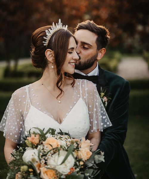 Bride in a dotted wedding dress and quartz crystal crown with the groom in a velvet suit jacket.