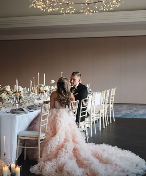 couple wearing peach tulle wedding dress and black groom tuxedo for formal wedding