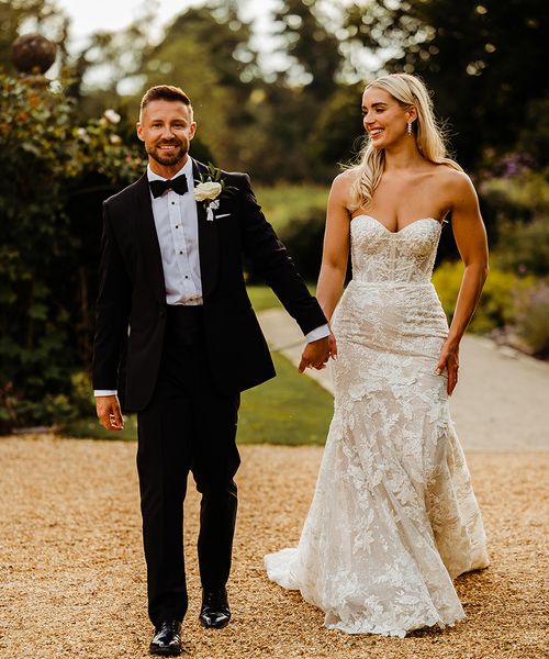 bride-wearing-lace-wedding-dress-with-groom-in-black-tuxedo-for-traditional-wedding