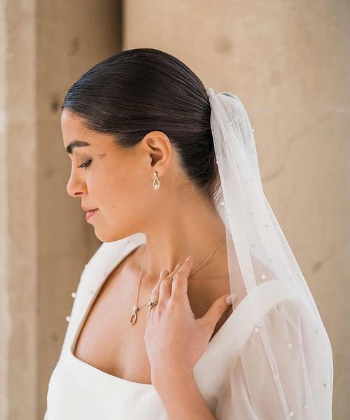 Bride in square neck wedding dress with sheer pearl embellished bridal veil and dainty silver pearl bridal jewellery