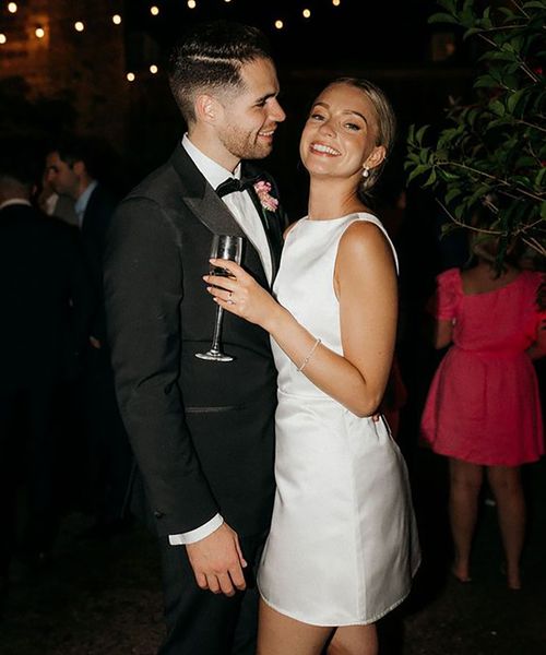 Bride in short wedding reception dress for the city wedding with the groom in a black tux