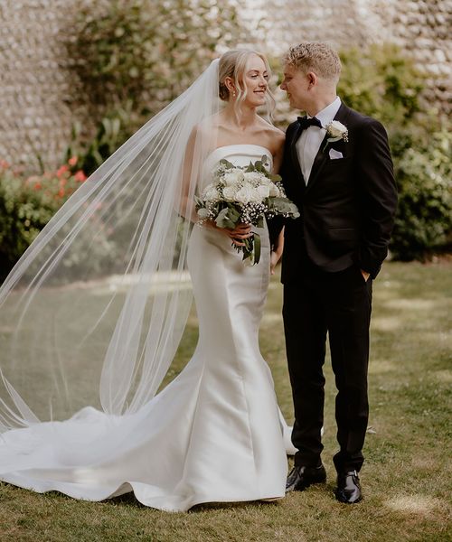 Mermaid wedding dress worn by the bride standing with groom in black tux