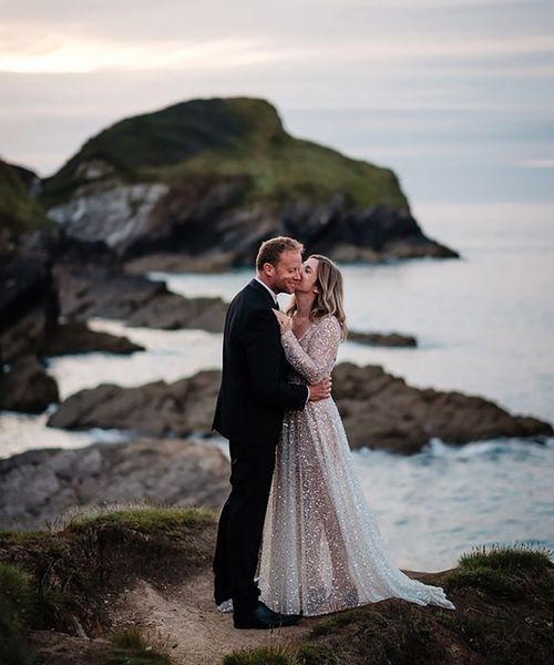 bride wearing a sparkly bespoke wedding dress by the sea on wedding day with groom