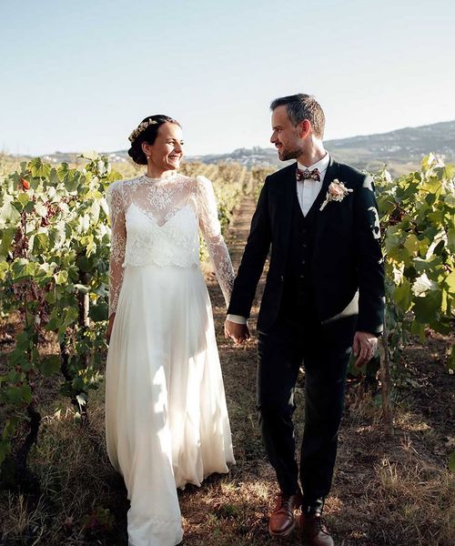 couple holding hands while walking through grapevine rows during their destination wedding at portugal vineyard venue