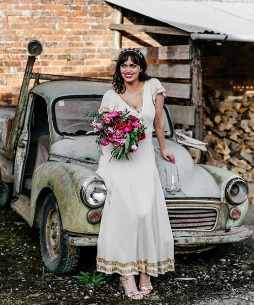 Bride wears vintage wedding dress with gold trim detail 