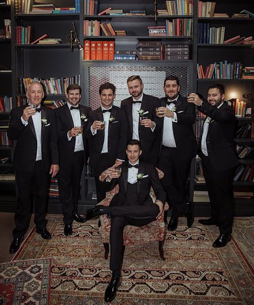 groom and groomsmen taking group photo on wedding day wearing matching black tuxedos