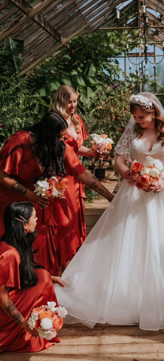 Bride in a princess tulle wedding dress with the bridesmaids in coral peach bridesmaid dresses.