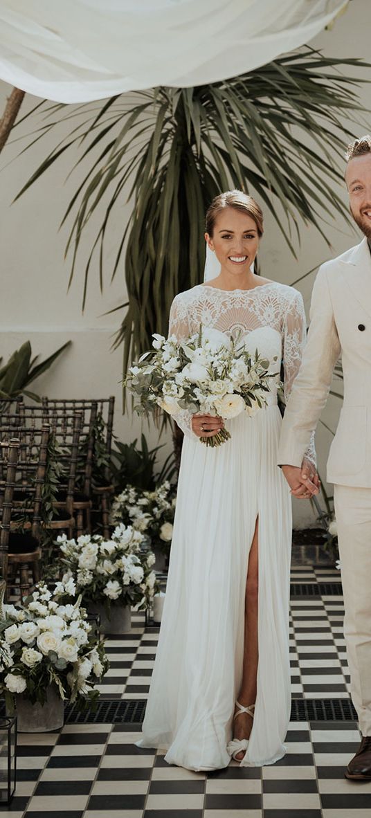 bride in lace Catherine Dean wedding dress with white wedding bouquet stands with husband in beige suit at Gunnesbury Park Orangery wedding altar