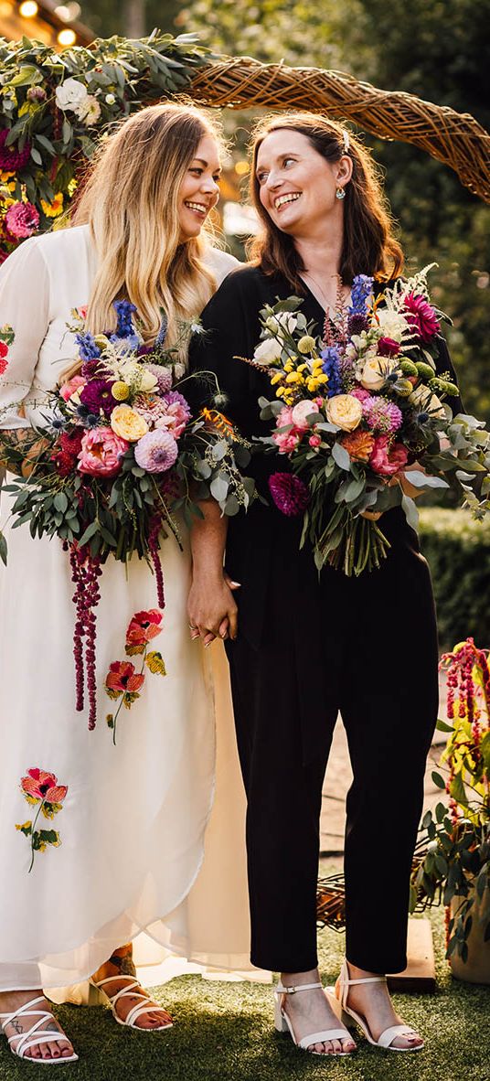 Two brides stand next to moongate decoration at seasonal at The Parlour wedding