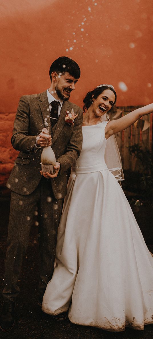 Rustic romance wedding theme for Devon wedding with the bride and groom popping champagne.