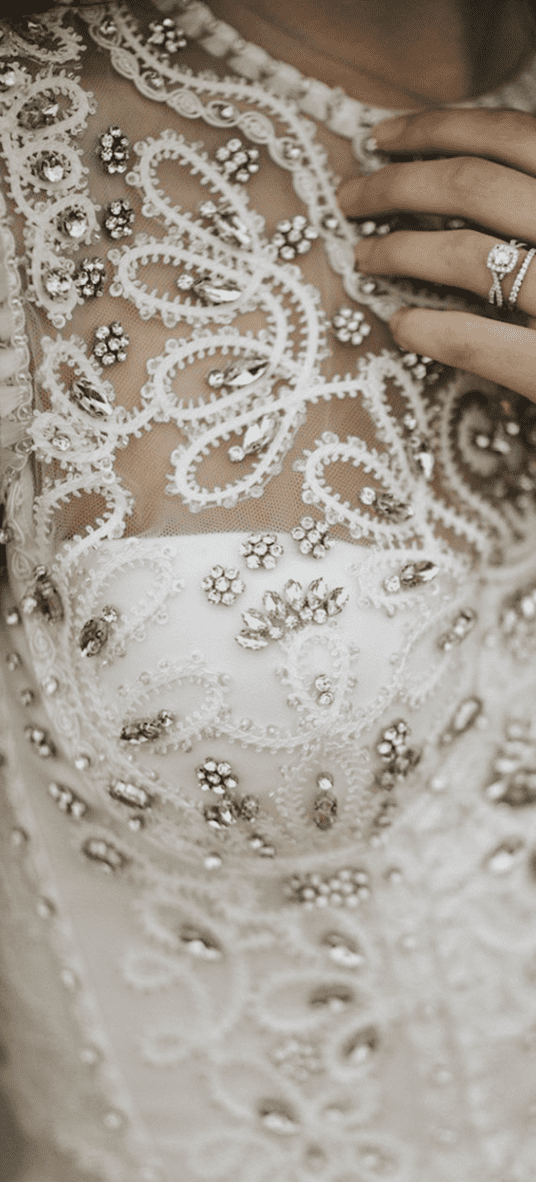 Bride in a bejewelled wedding dress wearing a sparkly engagement and wedding ring.