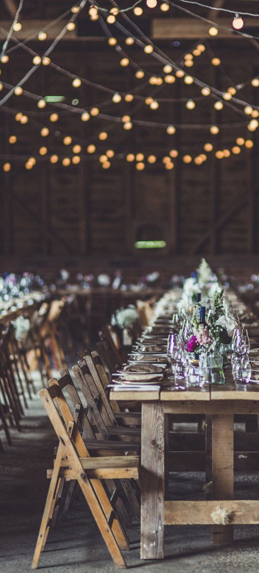 Rustic wedding ideas with fairy lights, trestle tables, tree slices, flowers in jars and wooden signs 