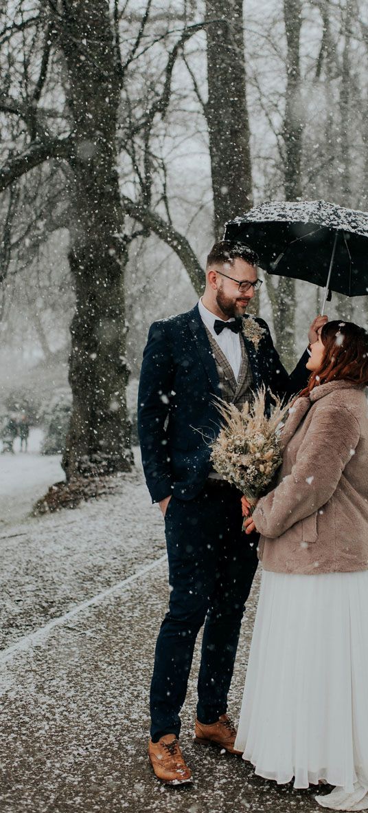 bride-and-groom-under-umbrella-at-snowy-winter-wedding