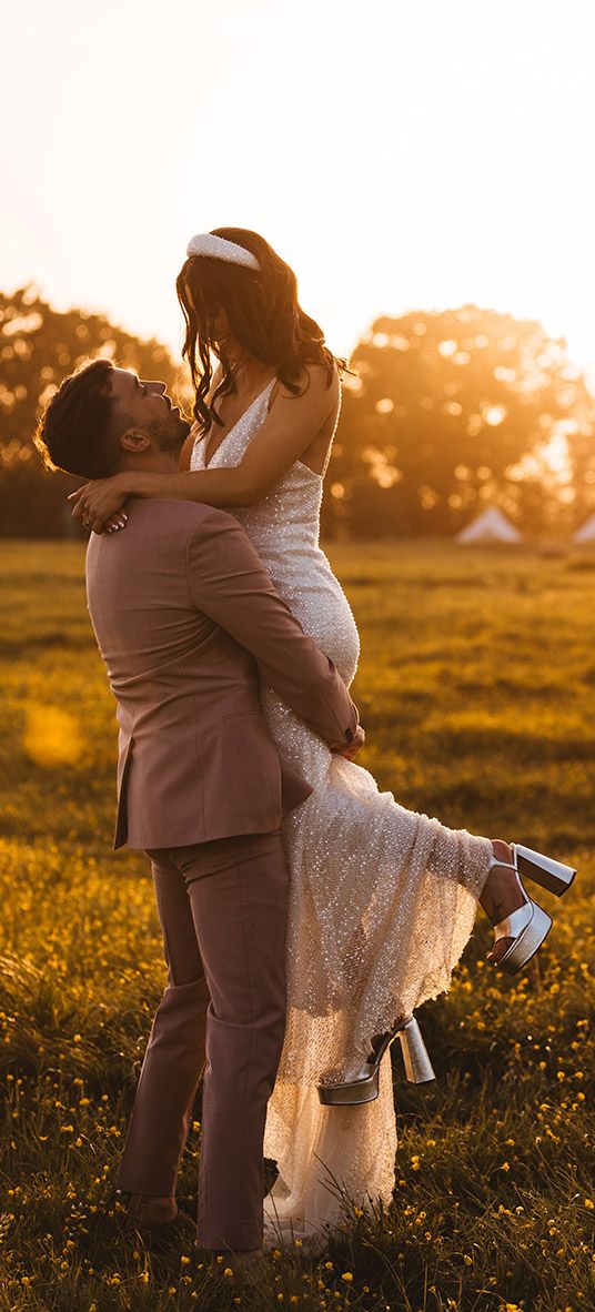 bride is lifted up by the groom for their golden hour wedding photos