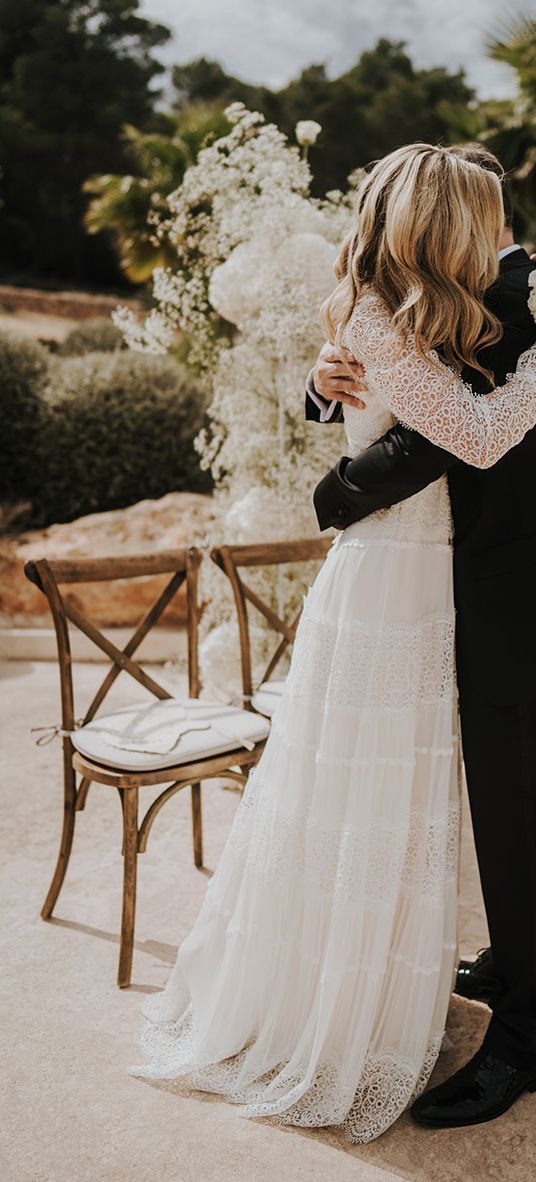 Intimate Pure House Ibiza wedding with white wedding flowers, wedding guests outfits & boho lace wedding dress by Balti Remeliai Photography