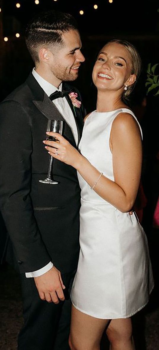 Bride in short wedding reception dress for the city wedding with the groom in a black tux