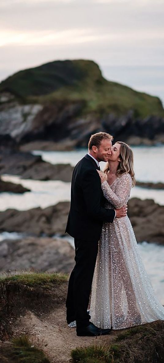 bride wearing a sparkly bespoke wedding dress by the sea on wedding day with groom