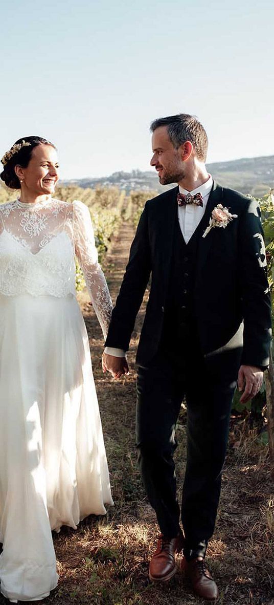 couple holding hands while walking through grapevine rows during their destination wedding at portugal vineyard venue