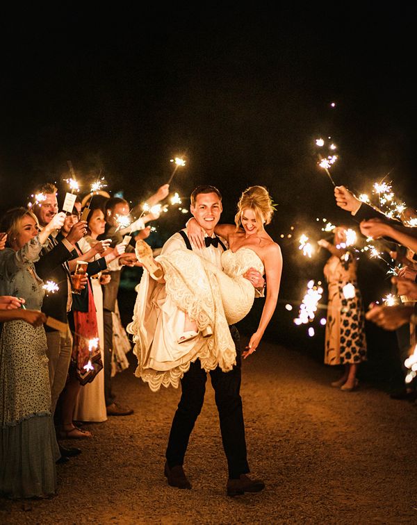 Groom lifting his bride in the air during their sparkler send off