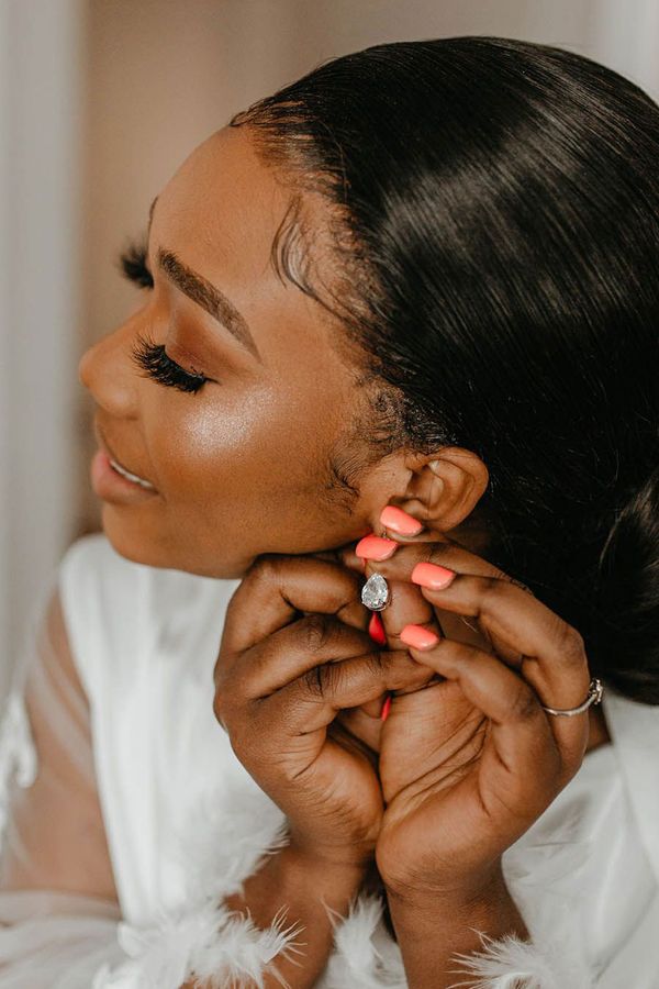 Bride putting on a pair of sparkly silver earrings on her wedding day