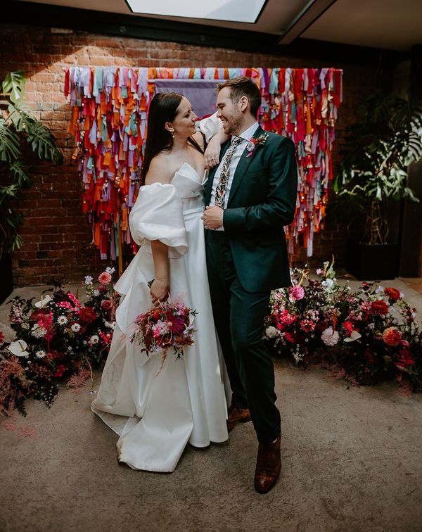 DIY rainbow streamers altar decoration with bride and groom
