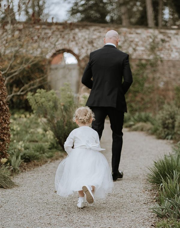 Flower girl in a white dress and cardigan to play a role in a wedding
