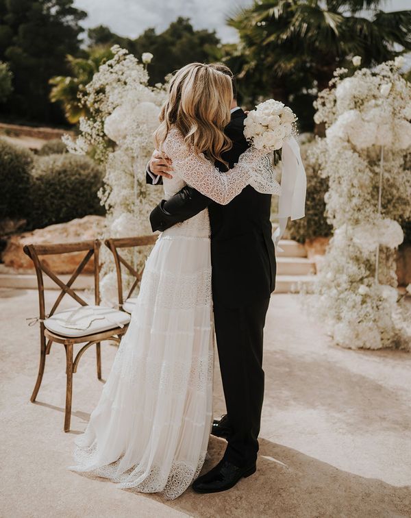 Intimate Pure House Ibiza wedding with white wedding flowers, wedding guests outfits & boho lace wedding dress by Balti Remeliai Photography