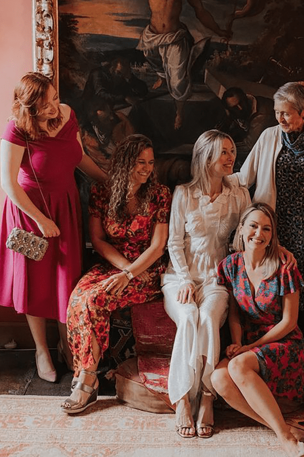 guests wearing casual wedding attire, including pink midi dresses and floral jumpsuits
