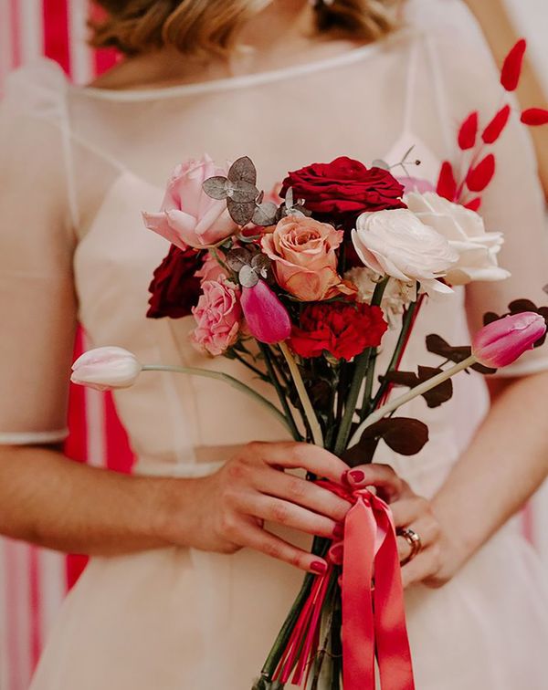 Bridal bouquet with white, pink and red garden roses, pink peonies and red dried decor with pink and red ribbon tied around for Valentine's Day theme wedding