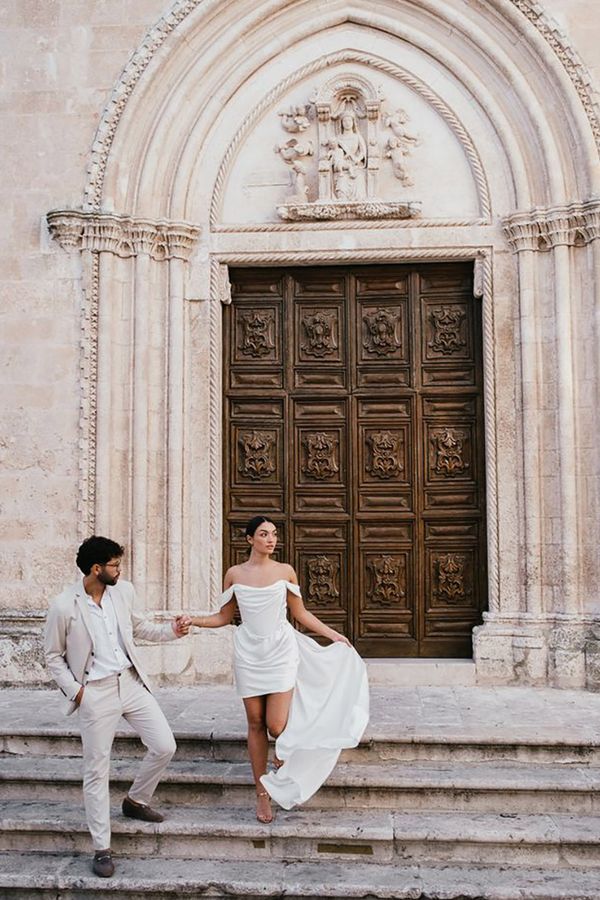 Destination wedding in Italy with bride wearing a short wedding dress and groom wearing neutral beige suit