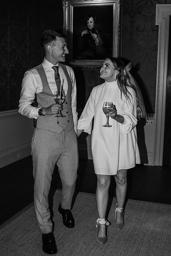 Bride in a short, high neck, long sleeve wedding reception dress as date night outfit idea with groom.