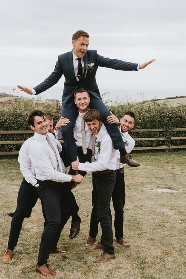 Groom sitting on groomsmen's shoulders for festival-themed wedding
